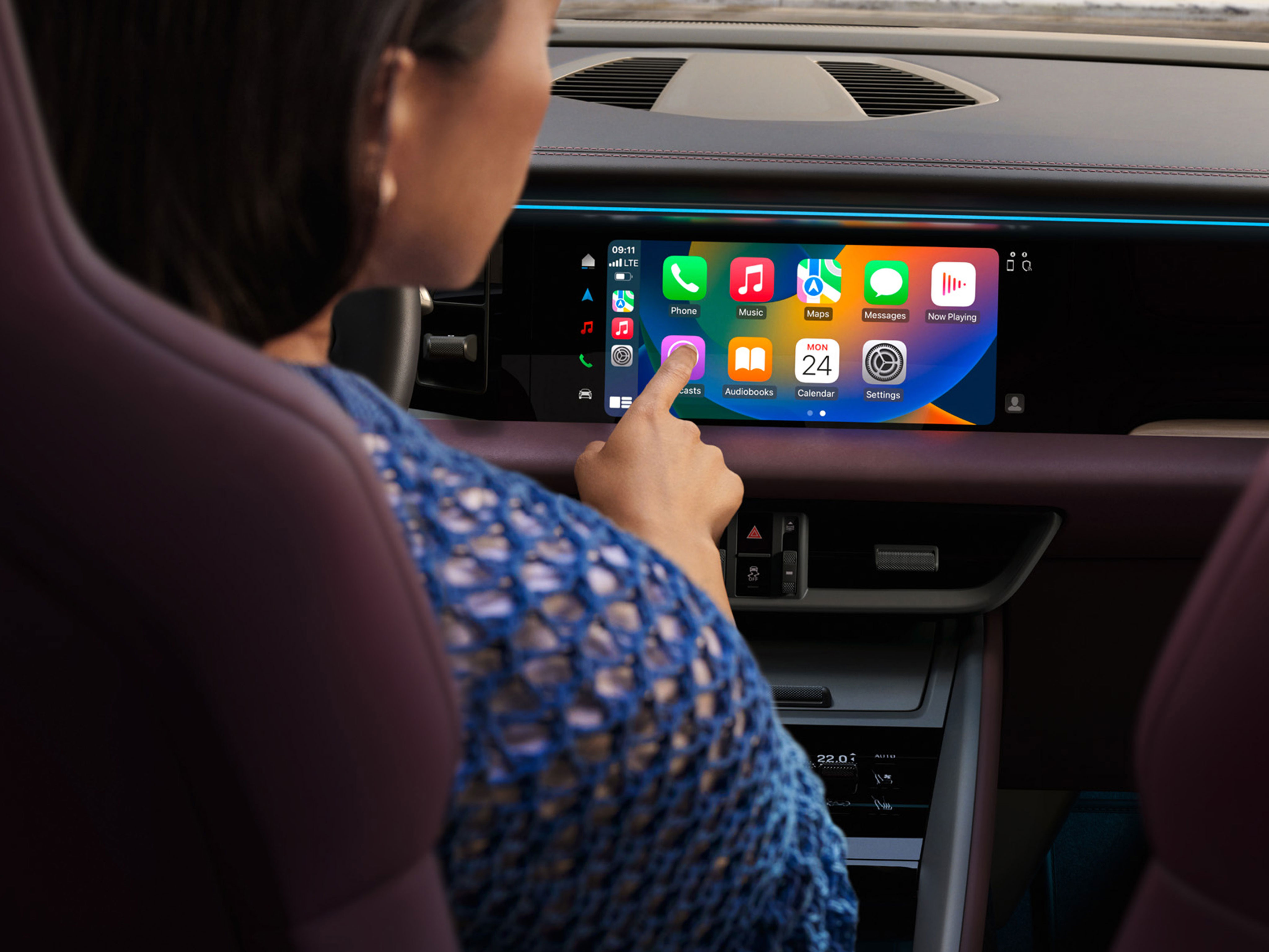 Frau in einem Macan Electric nutzt das PCM und bedient Apple Carplay.