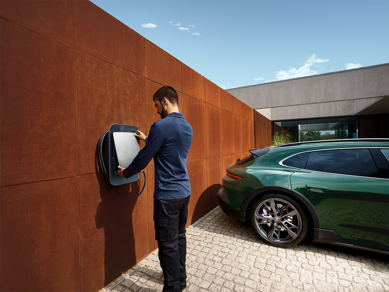 Bild, das einen Elektriker bei der Installation der Porsche Wallbox in einem Privathaushalt zeigt. 