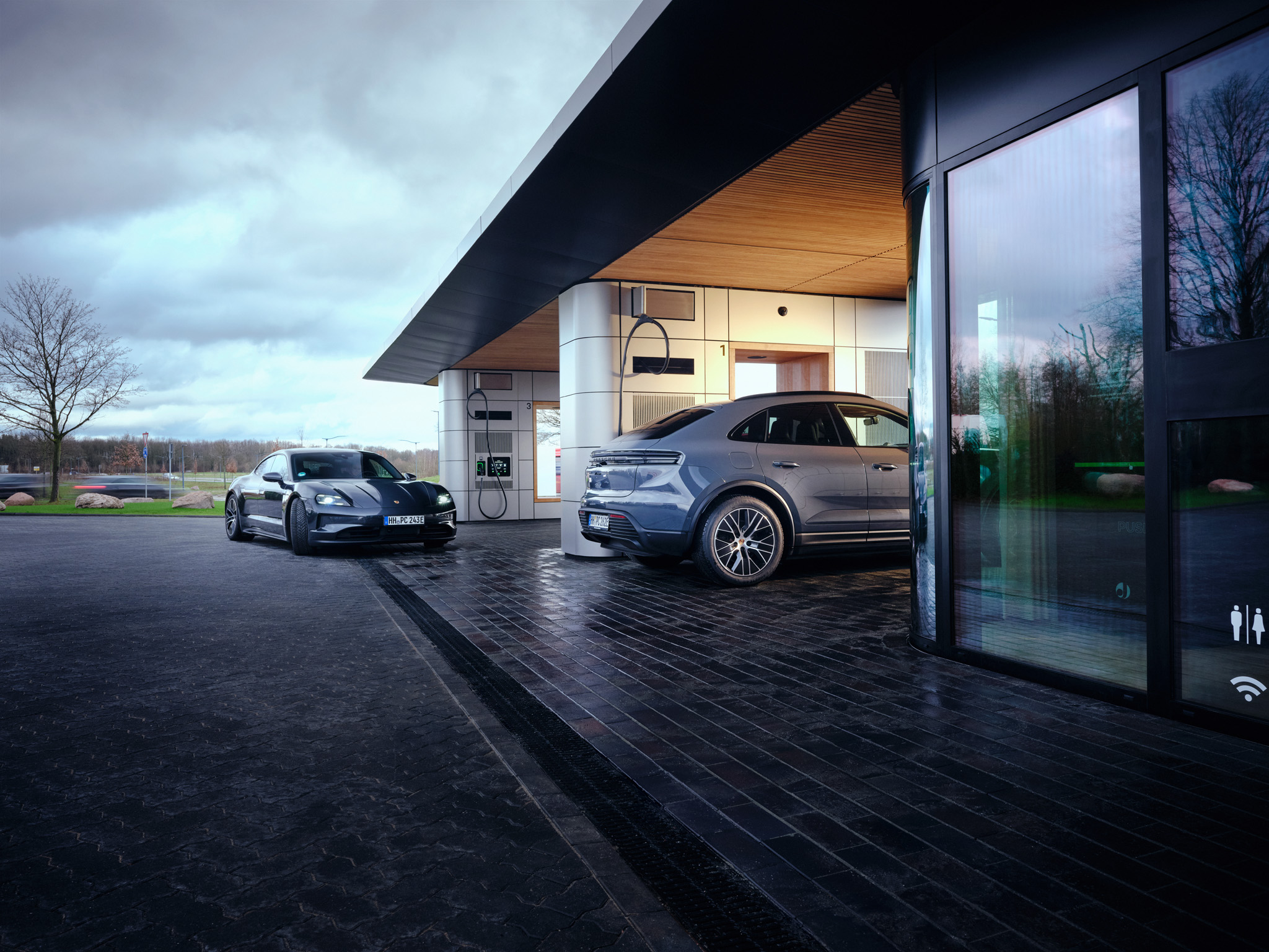 Porsche electric cars charging at premium EV station with modern architecture. Luxury electric mobility hub offering fast charging, sustainable travel, and high-end convenience for Taycan and Macan electric models.