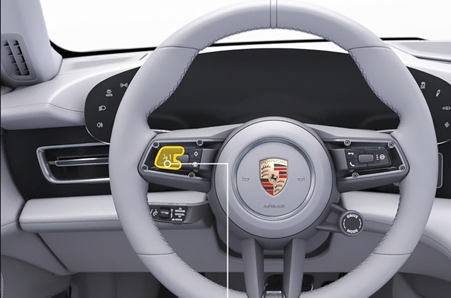Image of a Porsche steering wheel with an arrow pointing to the Android Auto Voice Control button.
