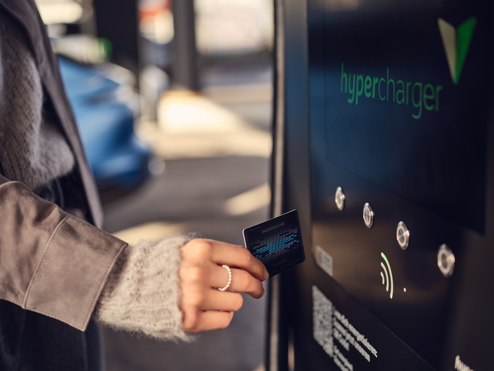 Gros plan sur l'utilisation d'une carte de recharge Porsche à une station Hypercharger EV. Accès à la recharge rapide des véhicules électriques haut de gamme avec authentification RFID, alliant commodité, mobilité intelligente et voyage durable.